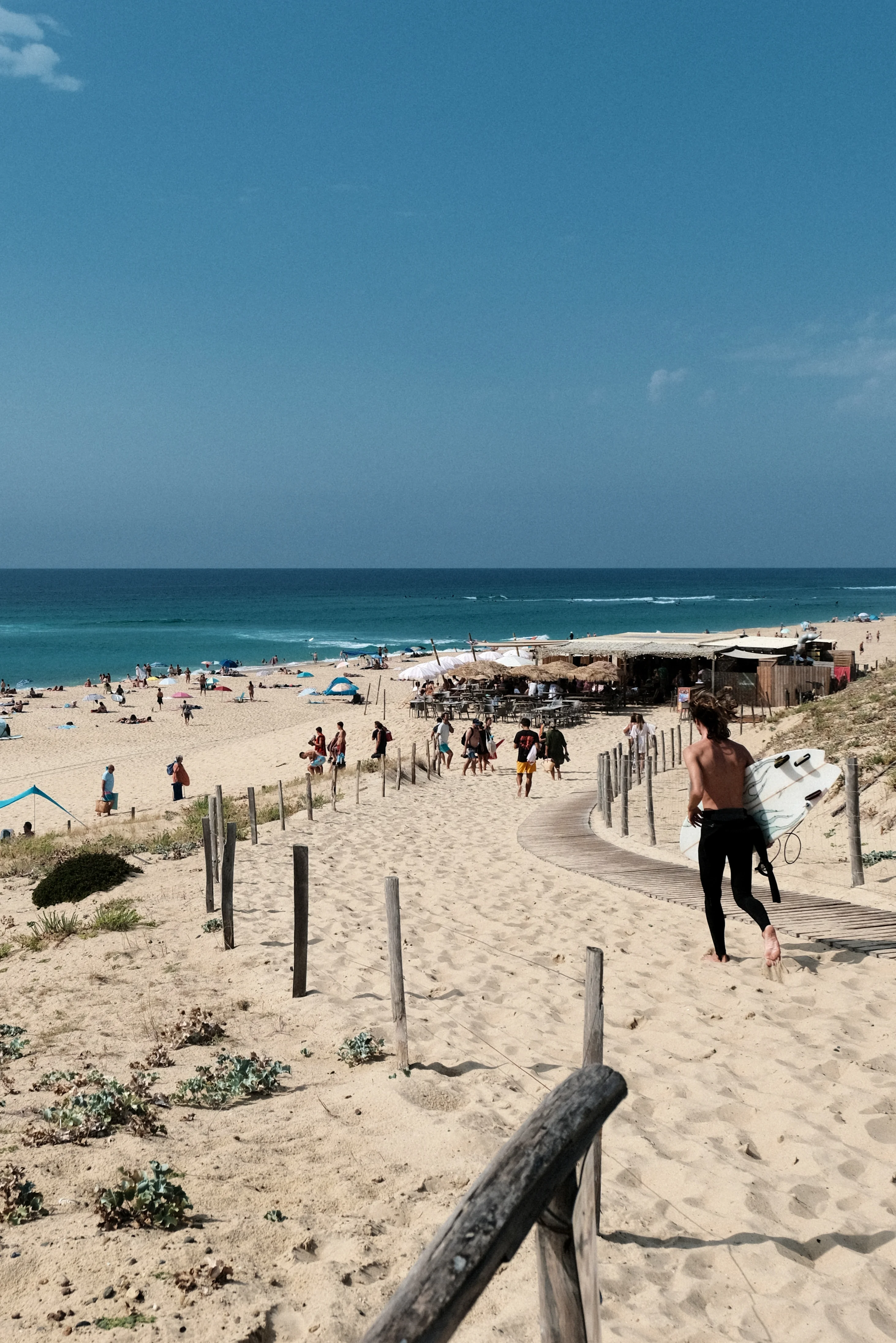 Surfer carrying a rental board on the path to Agréou, Seignosse